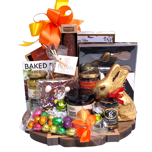 A charcuterie board loaded with gourmet mustard, salsa, artisanal salami, smoked salmon, crackers and cheese, olives, cheese topping, dip mix, pretzels and a classy cheese knife set.