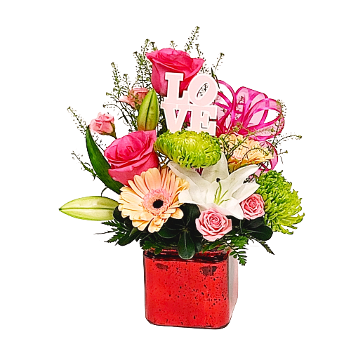A cube vase with a floral arrangement of soft coloured florals.