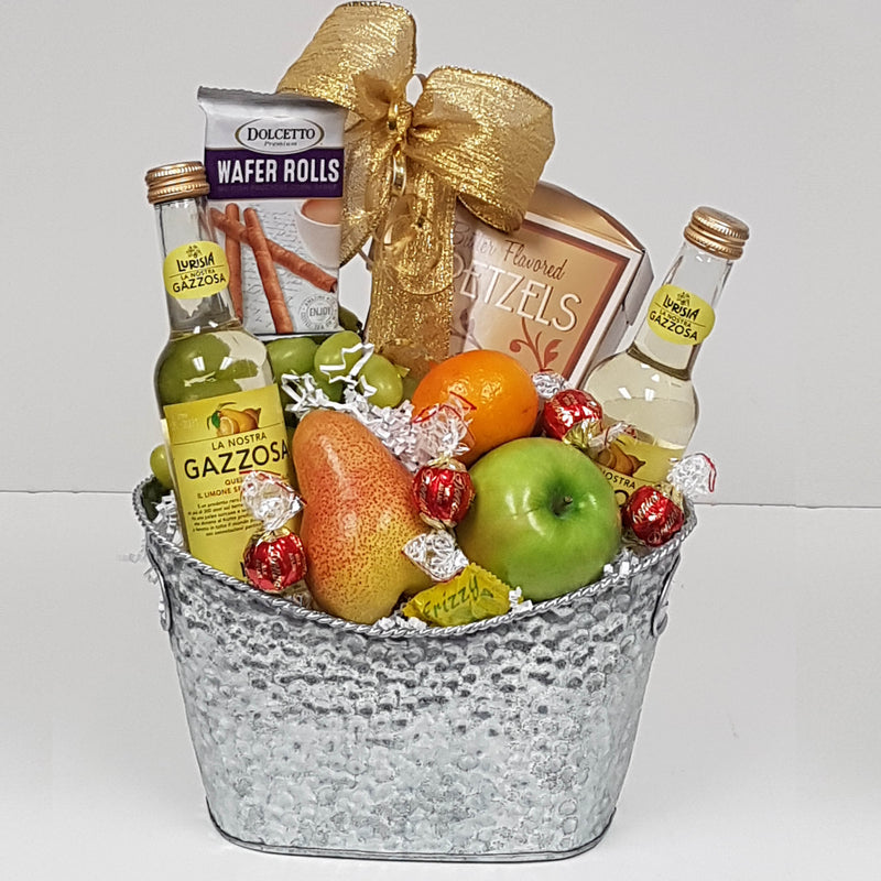 A silver tin with an assortment of fruit, sweet and salty treats, and some sparkling water, too.