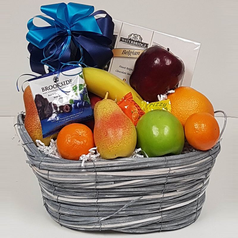 A basket with an assortment of fruits and some sweets.