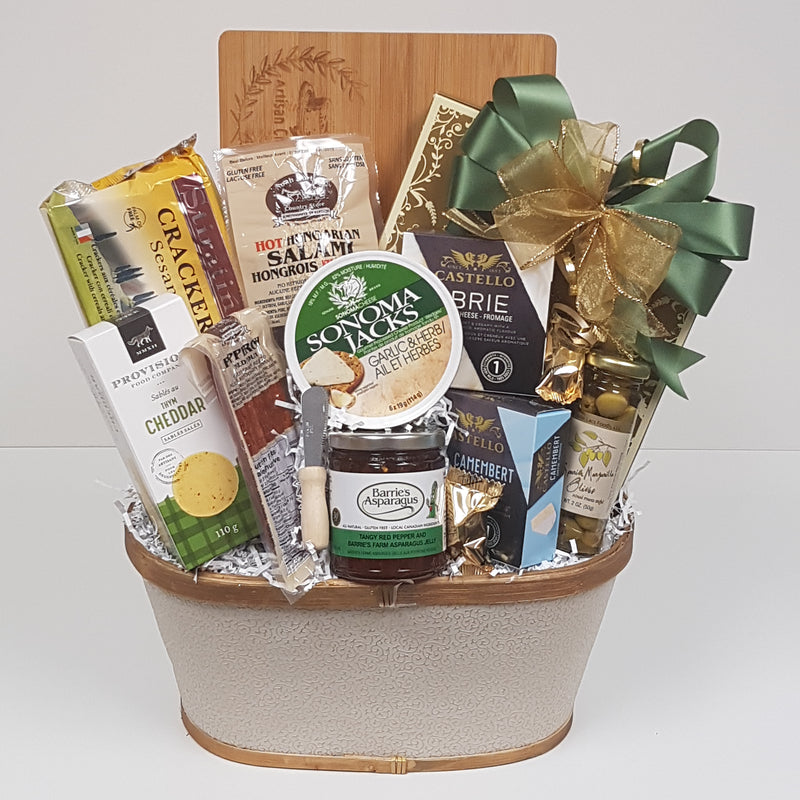 A basket filled with a cutting board, crackers and cheese, salami, olives, red pepper jelly, pepperoni, savoury shortbread and truffles.