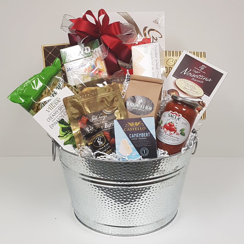 A silver tin loaded with European chocolates, all the fixings for a pasta dinner, Sea Change salmon, gourmet dip mix, cheese, crackers, coffee, tea, and biscuits.
