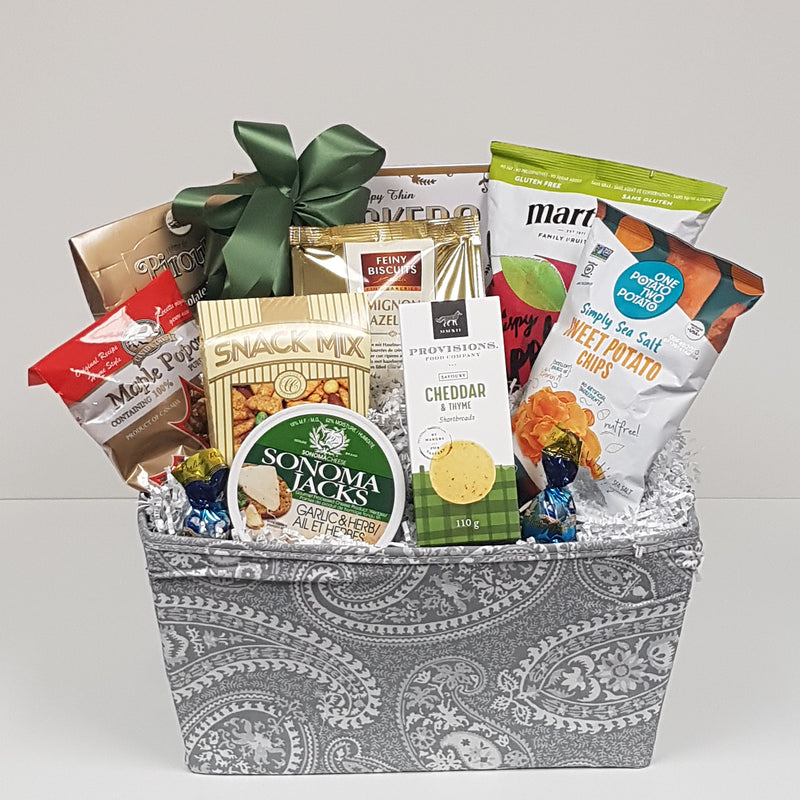 A basket with an assortment of sweet and salty snacks, cheese and crackers.