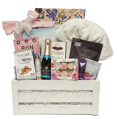 Wooden crate gift basket brimming with champagne, truffles, popcorn, cookies, gummies, tea and assorted bath indulgences.