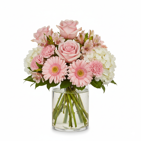 Clear glass vase arrangement of pink roses, gerberas, carnations, alstromeria and hydrangea. 