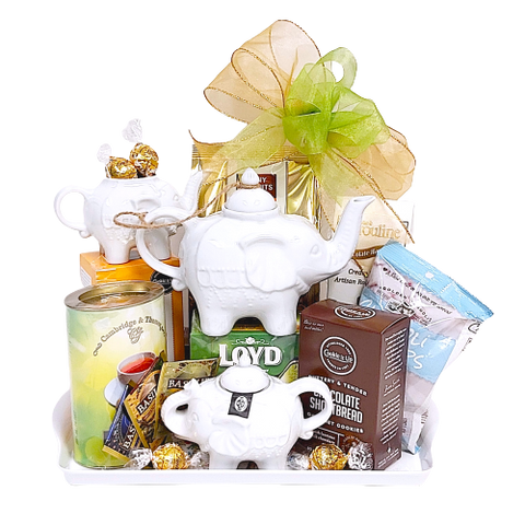An assortment of tea, biscuits, chocolate, and a teapot with matching creamer and sugar pot, on a tray.