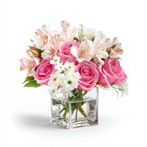Clear glass cube vase filled with pink roses, alstromeria and daisies.