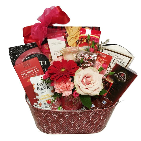 Red tin gift basket filled with shortbread, truffles, biscotti, coffee, tea, hot chocolate, nuts and a beautiful flower arrangement.