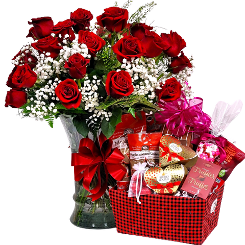 An arrangement of two dozen red roses with a gift basket of sweet treats.