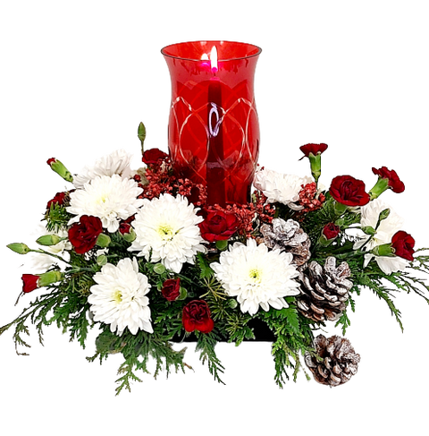 A red glass chimney with a candlestick in the center, surrounded by Christmas greenery and red & white blooms.