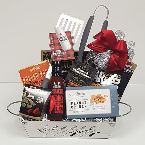A stainless steel grill basket with a set of BBQ utensils, BBQ sauce and seasonings, bar mix munchies, truffles and peanut crunch.