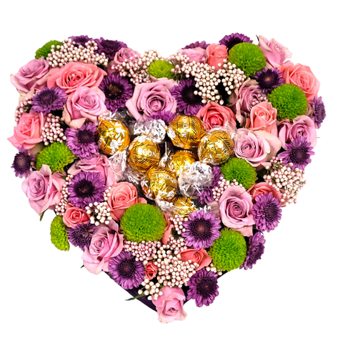Heart-shaped floral design with pink and lavender roses, poms and asters topped with Lindt truffles.