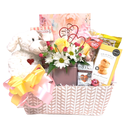 Nestled inside this pretty basket is a cute floral arrangement, a cuddly plush animal along with sweet treats of chocolate, shortbread, cookies and more to warm the heart.